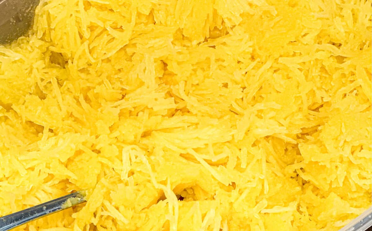 A close up of bright yellow strands of cut spaghetti squash ready to serve.