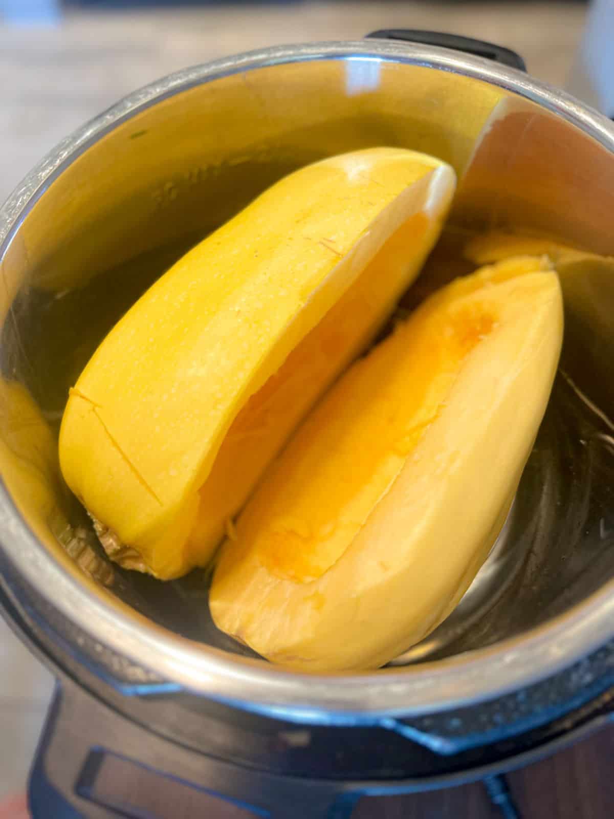 a picture looking into an instant pot with two spaghetti squash halves in it, ready to cook.
