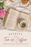 A photo of a book opened with a dainty coffee or tea cup and saucer on it surrounded with crumpets and flowers. At the bottom reads Acidity of Tea vs Coffee MindfullyHealthyLiving.com
