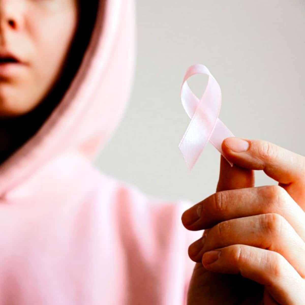 a person in pink holding a ribbon that represents fighting cancer