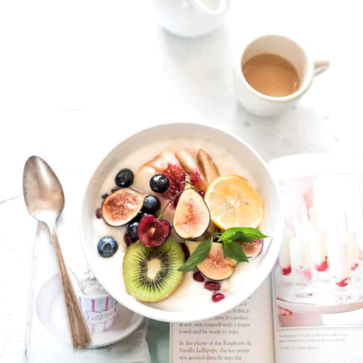 a bowl of fruit set on top of a book about healthy food