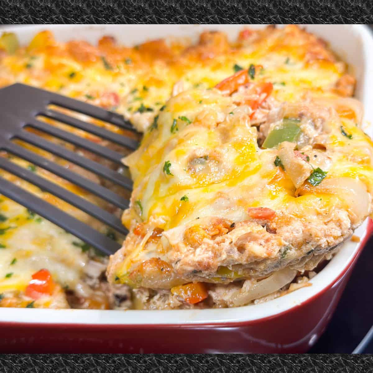 keto chicken fajitas with melted cheese on top is being scooped from a red baking dish with a black serving spatula.