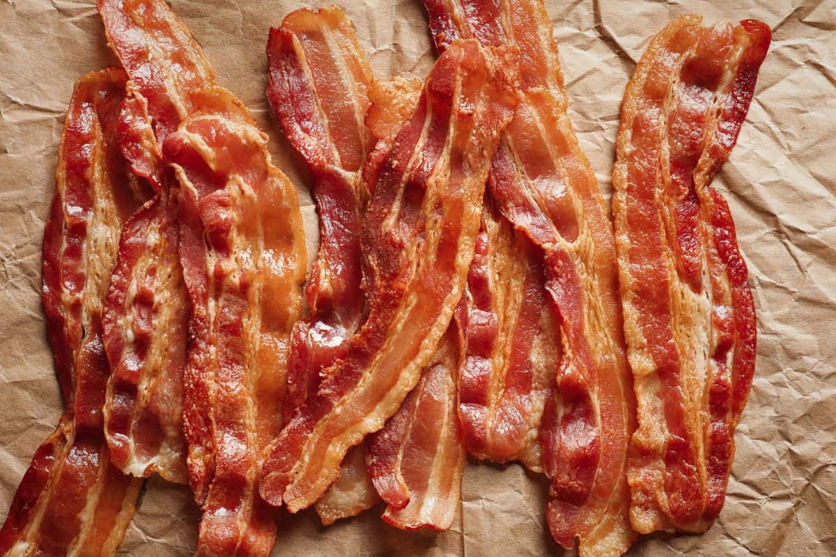 A stack of cooked bacon strips laying on a brown parchment paper