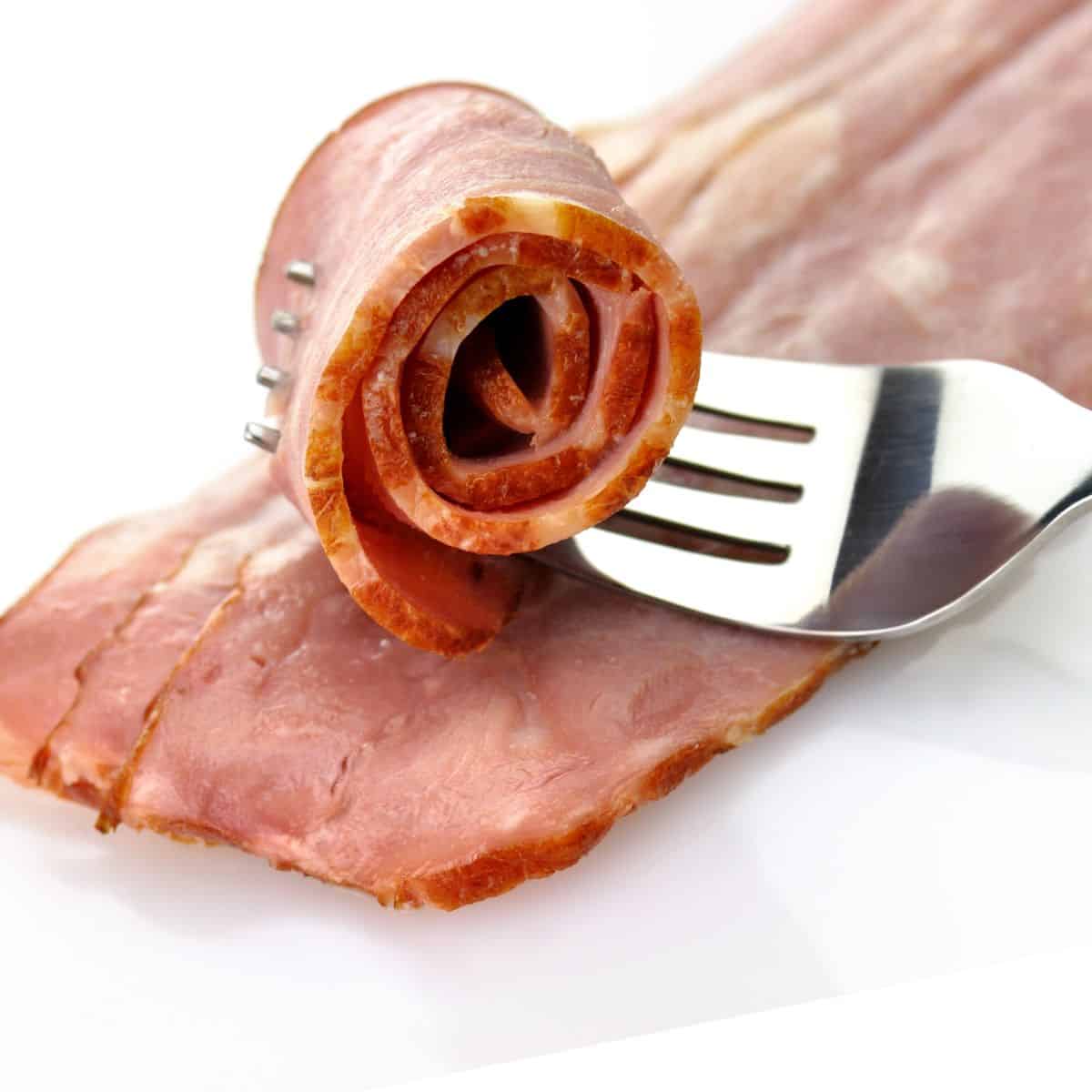 a diagnally placed stack of turkey bacon slices with one rolled up with a fork through it
