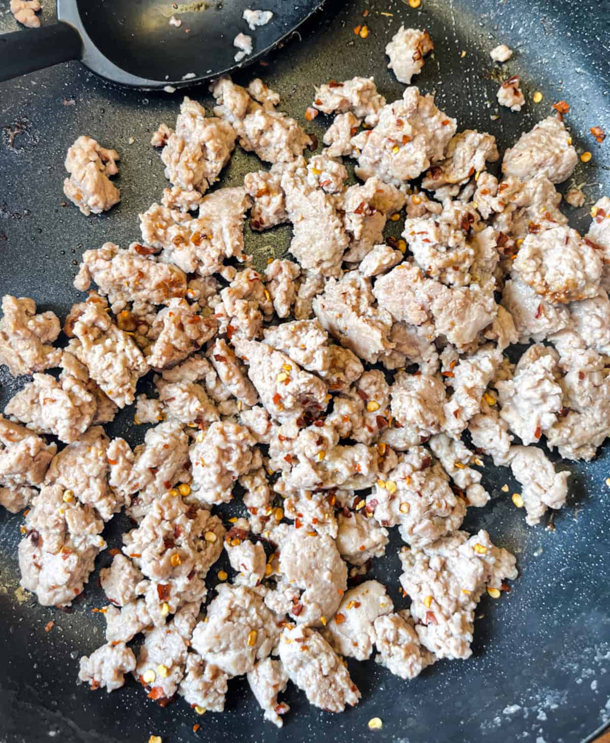 cooked turkey sausage in a skillet with red pepper flakes