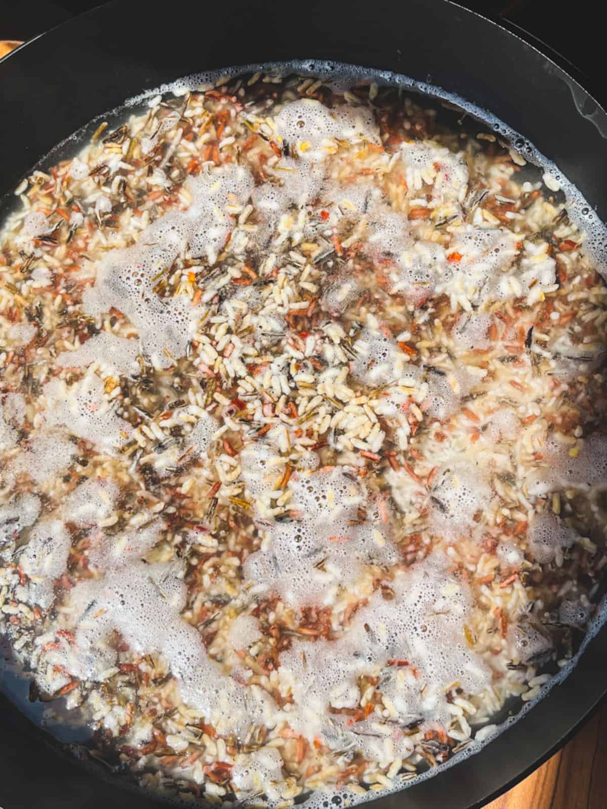 wild rice cooking in water in a skillet