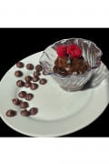 a white plate with clear decorative bowling brown chocolate pudding in it topped with two red raspberries with a side of chocolate chips