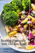 a grey bowl on a blue and white placemat with broccoli, shredded jerk chicken, chopped pineapple, red onions, black beans, and cilantro on a bed of rice with a print in black that says Healthy Pineapple Jerk Chicken Bowl at the bottom left