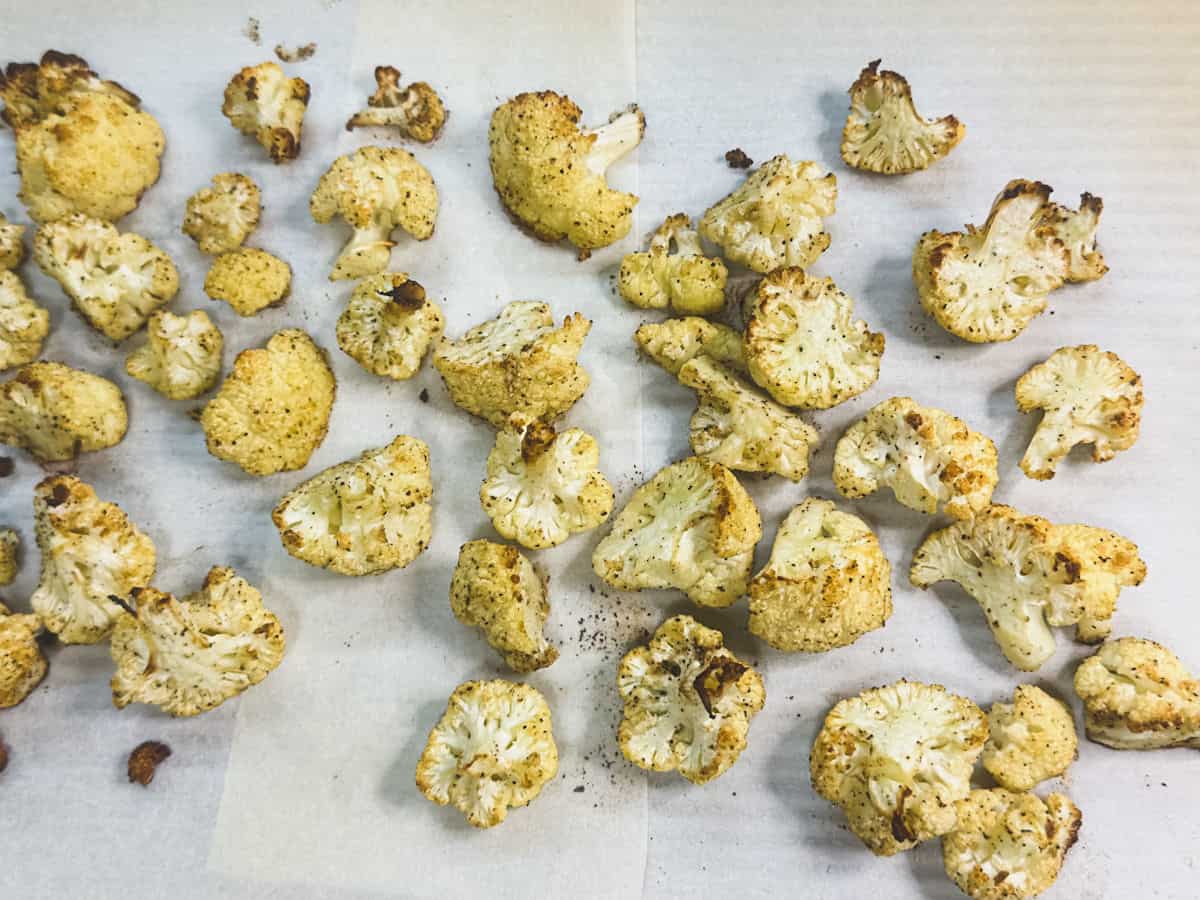 roasted cauliflower on parchment paper seasonmed with pepper