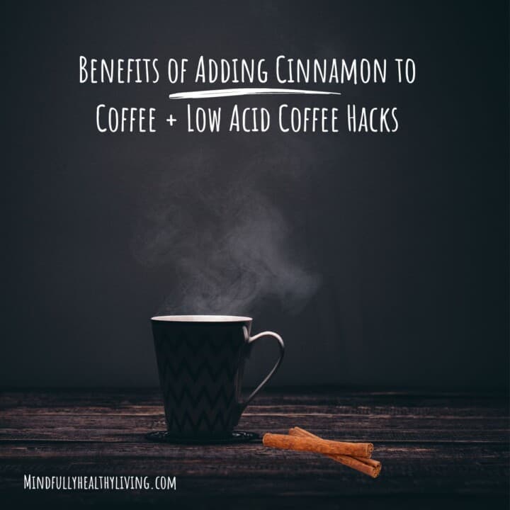 A dark grey background with all capital white lettering at the top that reads benefits of adding cinnamon to coffee + low acid coffee hacks. a dark wood table at the bottom has a tall mug of coffee in the shadow with the light only on the white interior without showing the coffee it shows a small steam coming from it. the cup appears to be white with four black zig zag patterns from left to right and a handle facing the right on a decorative black coaster. At the bottom reads all caps mindfullyhealthyliving.com with two crossed cinnamon sticks to the right of it