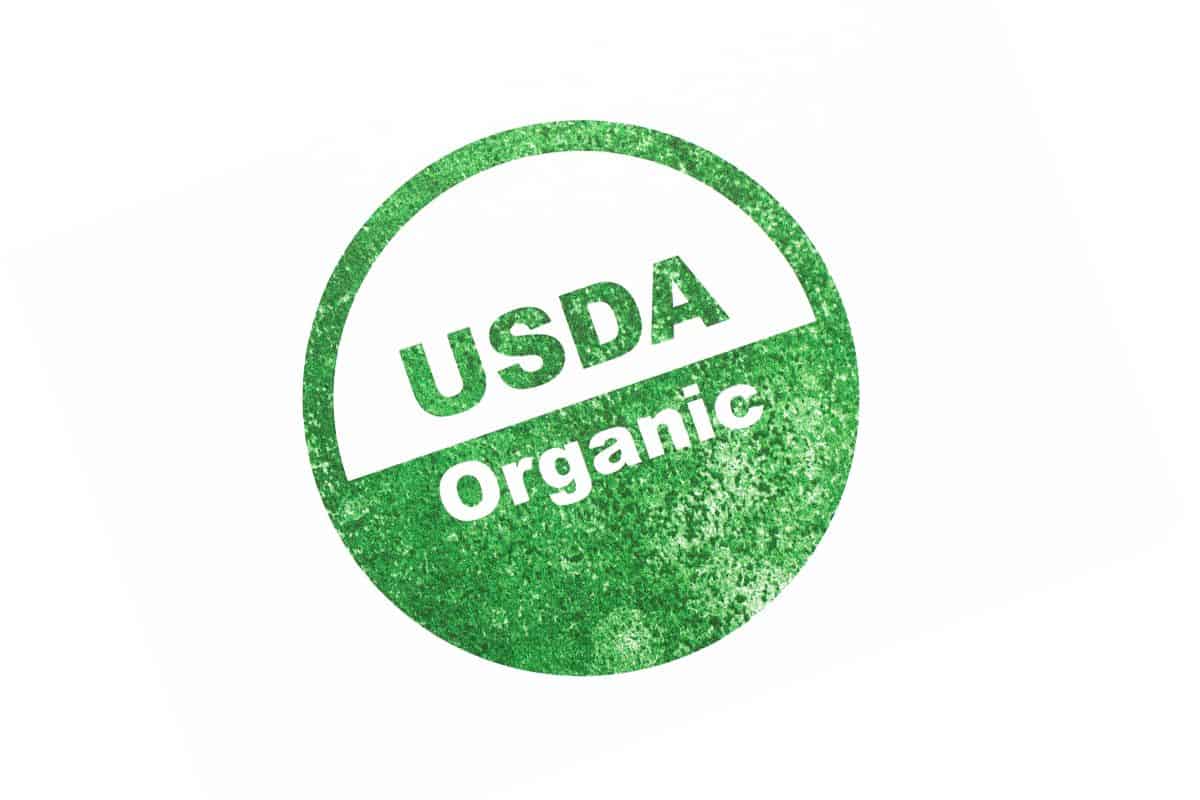 A left tilted circle of USDA Organic symbol in green and white with a faded appearance.