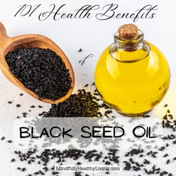 a rounded glass container filled with yellow black seed oil with a cork in it next to a wooden scoop of black seeds in it and scattered around it. Text overlay reads 101 Health Benefits of Black Seed Oil MindfullyHealthyLiving.com