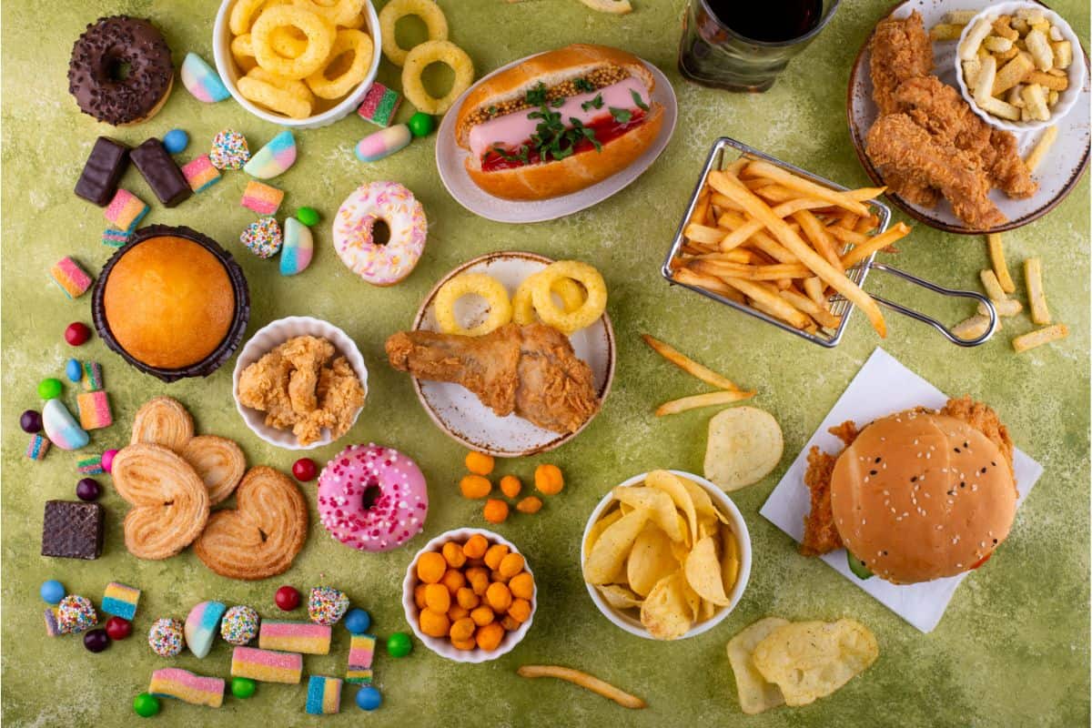 a photo of several ultra-processed foods, fast foods, candy, and junk food laid out to show which foods to avoid in a processed-free diet.