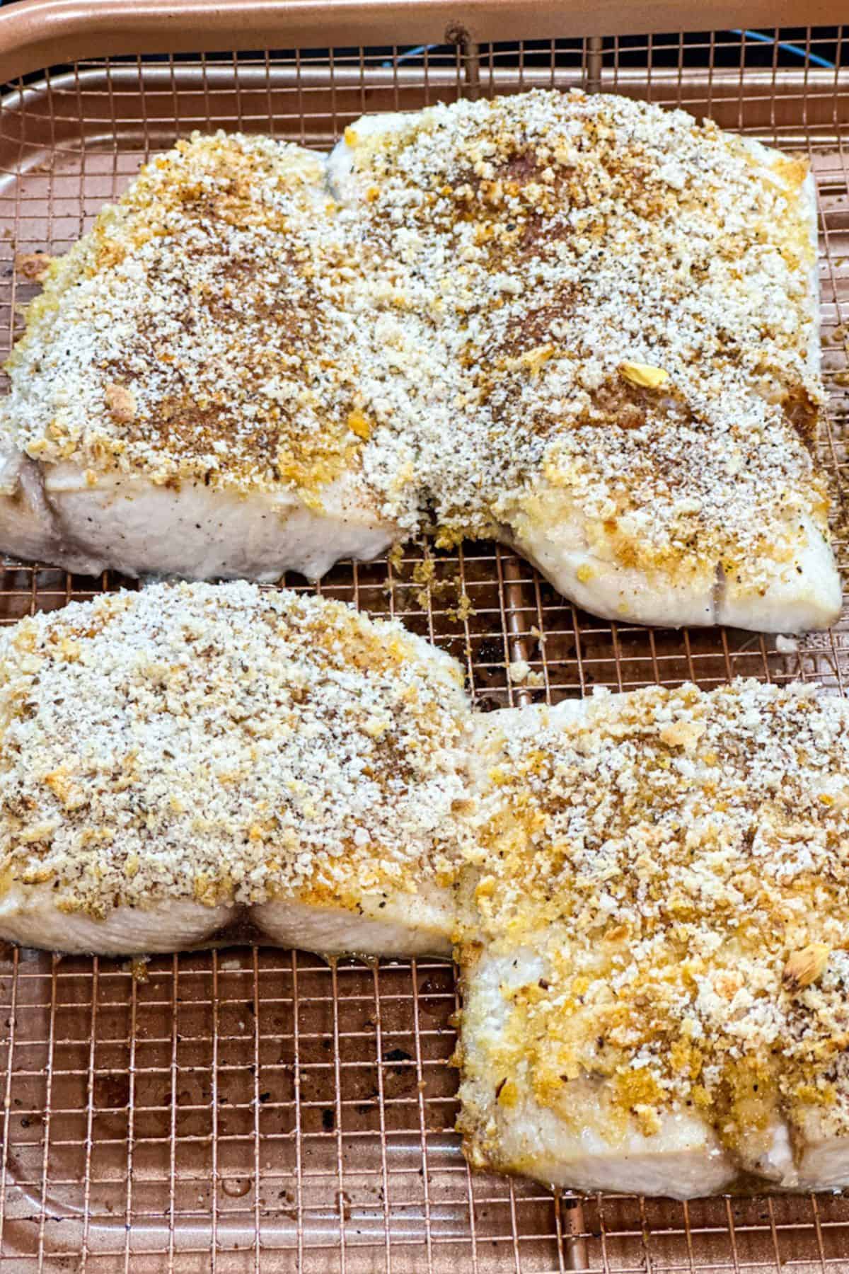 A close up of just air fried Mahi filets with golden drown pink crust on a bronze air fryer basket