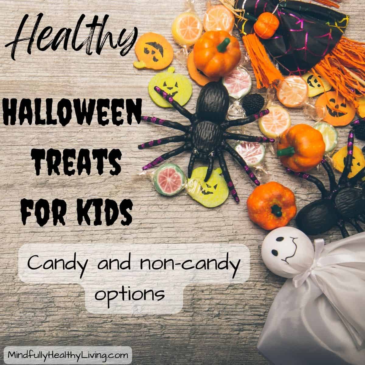 A wooden backdrop with Halloween decorations on the side like a ghost, pumpkin, spider, candies, and pumpkin cutouts. In the middle is spooky text that says healthy Halloween treats for kids candy and non-candy options mindfullyhealthyliving.com
