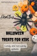 A Pinterest-optimized image of A wooden backdrop with Halloween decorations on the side like a ghost, pumpkin, spider, candies, and pumpkin cutouts. In the middle is spooky text that says healthy Halloween treats for kids candy and non-candy options mindfullyhealthyliving.com