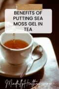 A white tea cup on a saucer with a spoon filled with tea and text overlay reads benefits of putting sea moss gel in tea on a sticky note. at the bottom says mindfullyhealthyliving.