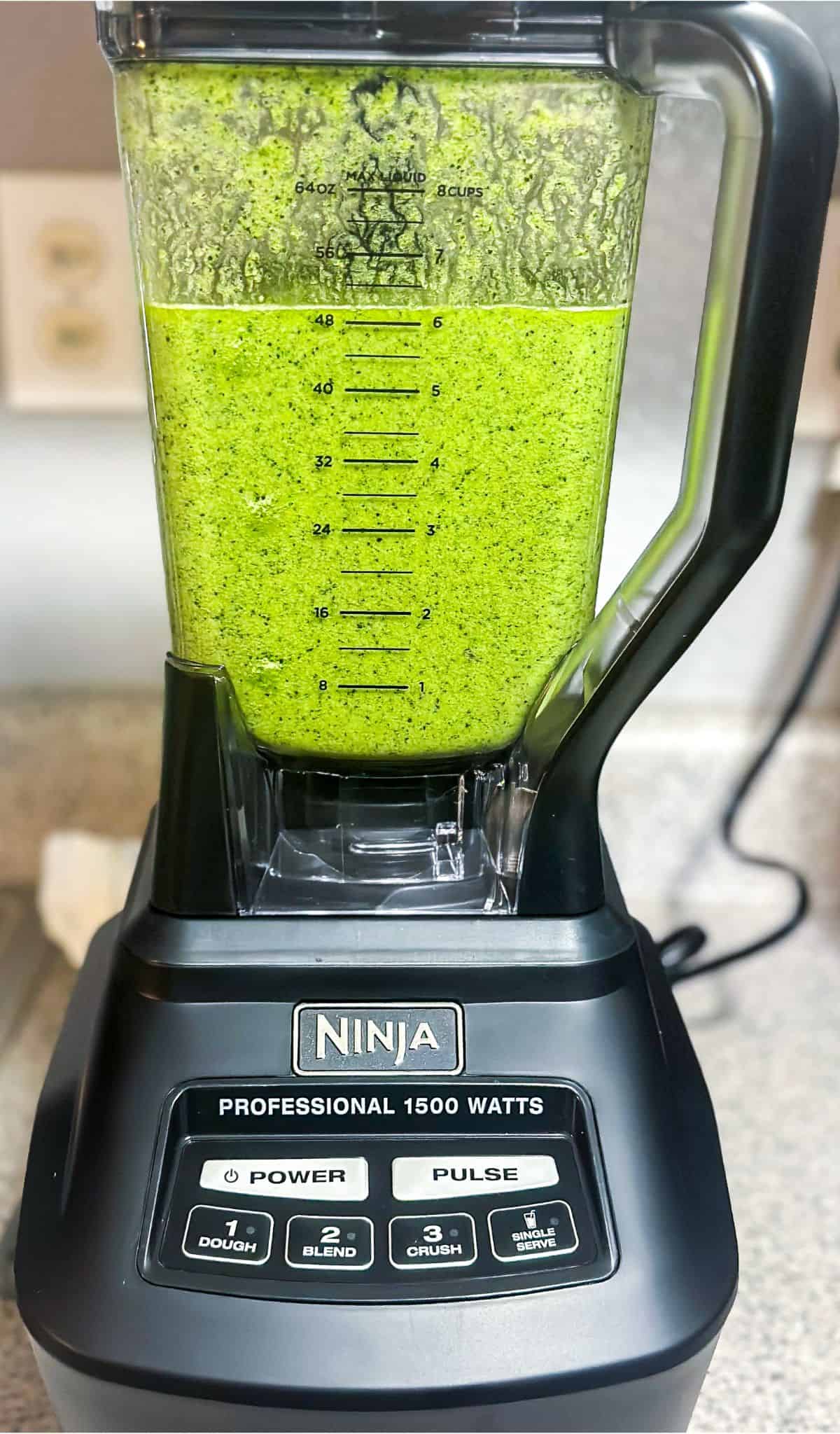 A high-speed black ninja blender filled with smooth green smoothie ready to serve.