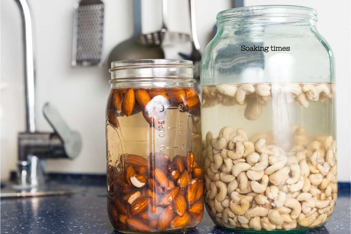 Two jars both filled with water. one also has almonds and the other, a slightly larger jar has cashews soaking. text overlay says "soaking times"