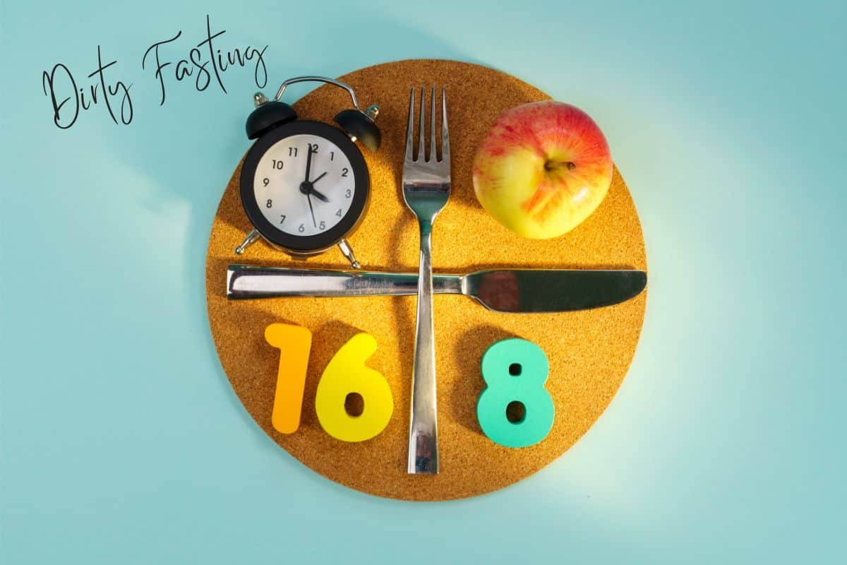 A round coaster on sponge board material that has a fork at 12 o'clock and a butter knife at 3 o'clock with a clock, an apple, the yellow number 16, and a green number 8 in the 4 quadrants. in the left upper side it reads dirty fasting.