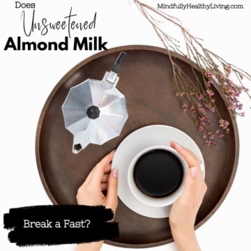 A brown serving tray with a white coffee mug and saucer that a woman's hands are holding. Next to it is a silver kettle and a sprig of tiny flowers. text overlay says does unsweetened almond milk in coffee break a fast? mindfullyhealthyliving.com