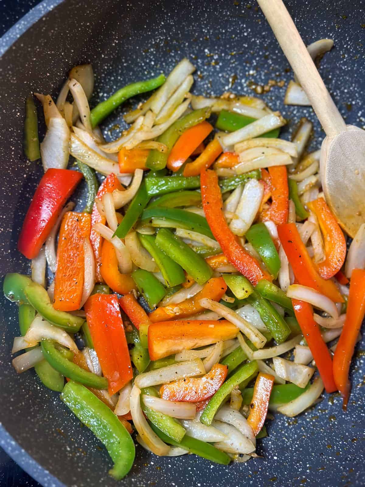 Sautéed onions and bell peppers in a skillet, seasoned for the base of a flavorful Cajun Smothered Chicken dish.