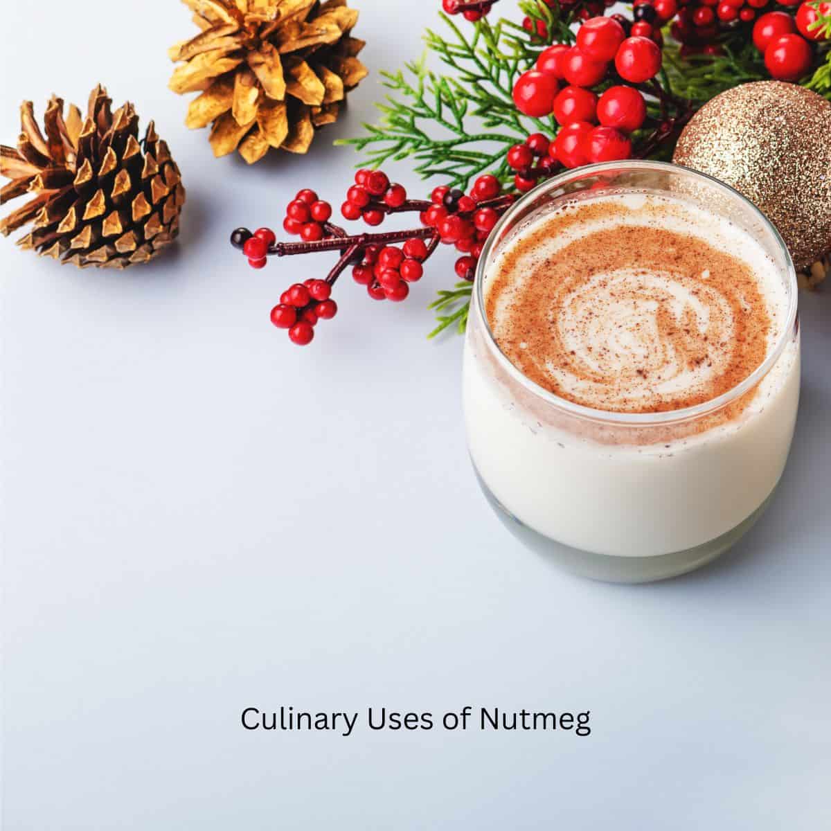 A glass of eggnog with nutmeg sprinkled on top, surrounded by festive holiday decorations.