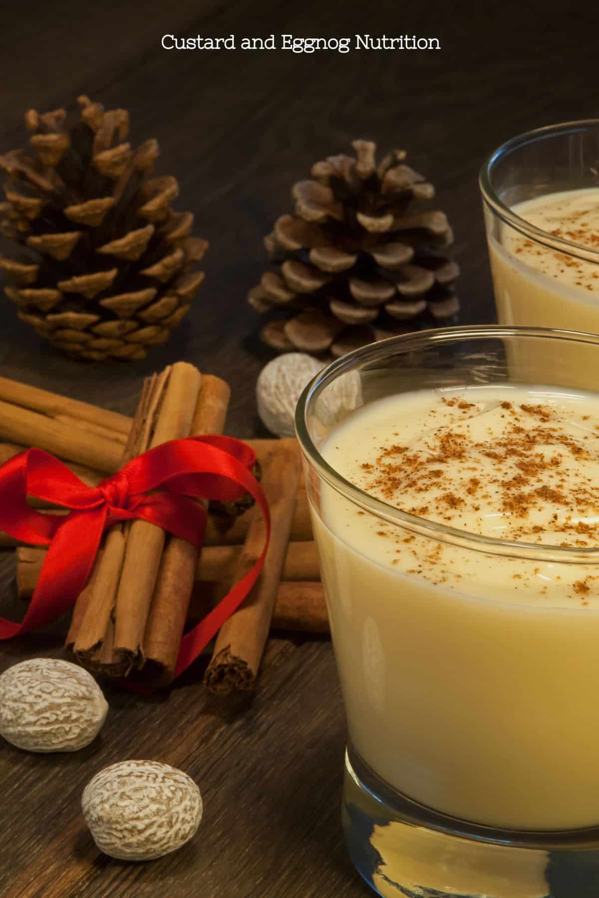 Festive setting with glasses of eggnog, cinnamon sticks, pine cones, and nutmeg suggesting holiday dessert nutrition.