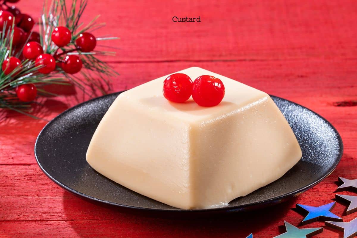 A traditional custard dessert topped with cherries on a black plate, set against a red festive background.