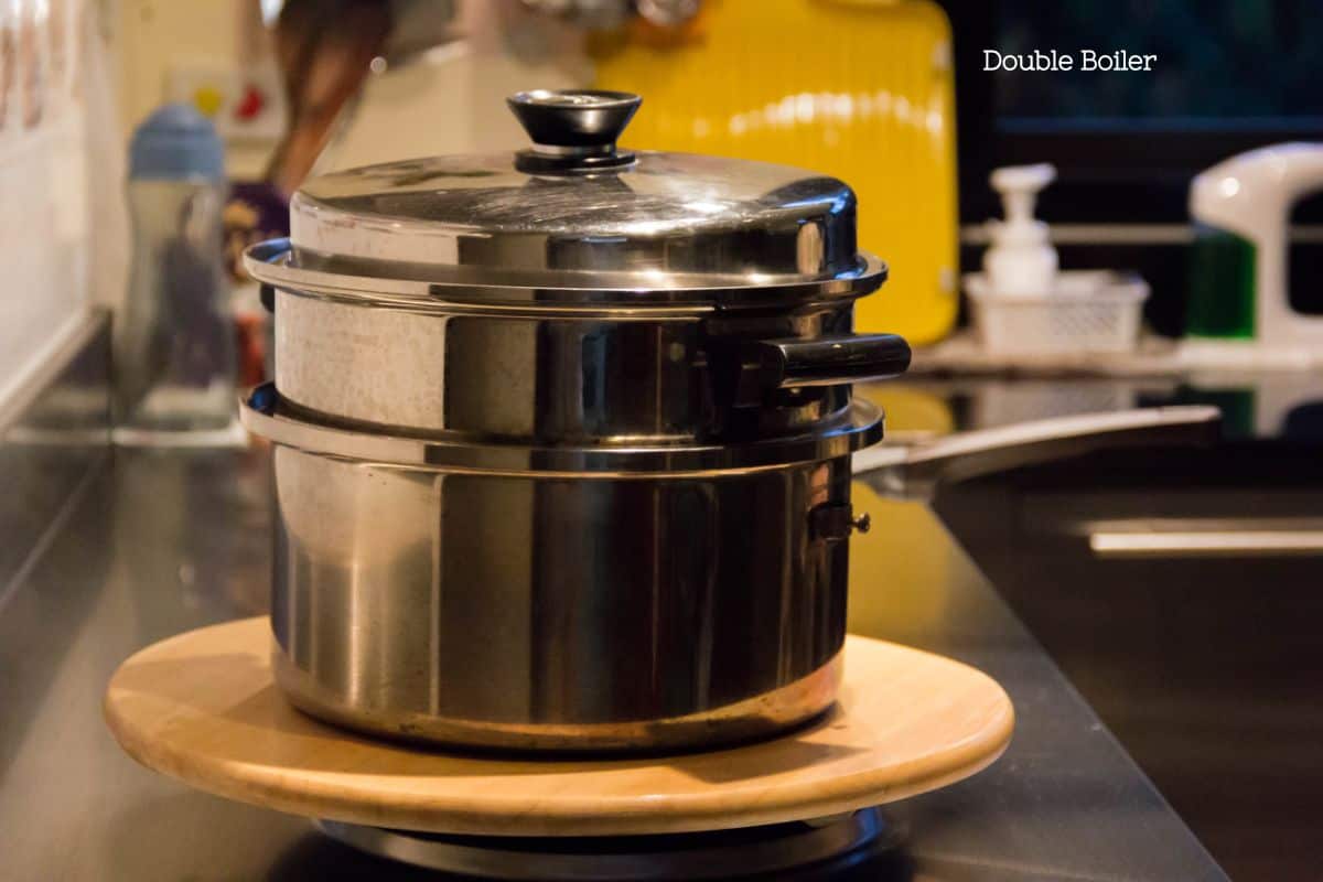 A kitchen setup showing a stainless-steel double boiler on a stove, a key tool for gently cooking custard.