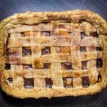 Freshly baked peach cobbler in a red baking dish, showcasing a browned lattice crust