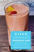 A photo of a glass of pineapple surf smoothie drink in the background with a blue box of white text that says clean copycat pineapple surf smoothie king recipe mindfullyhealthyliving.com
