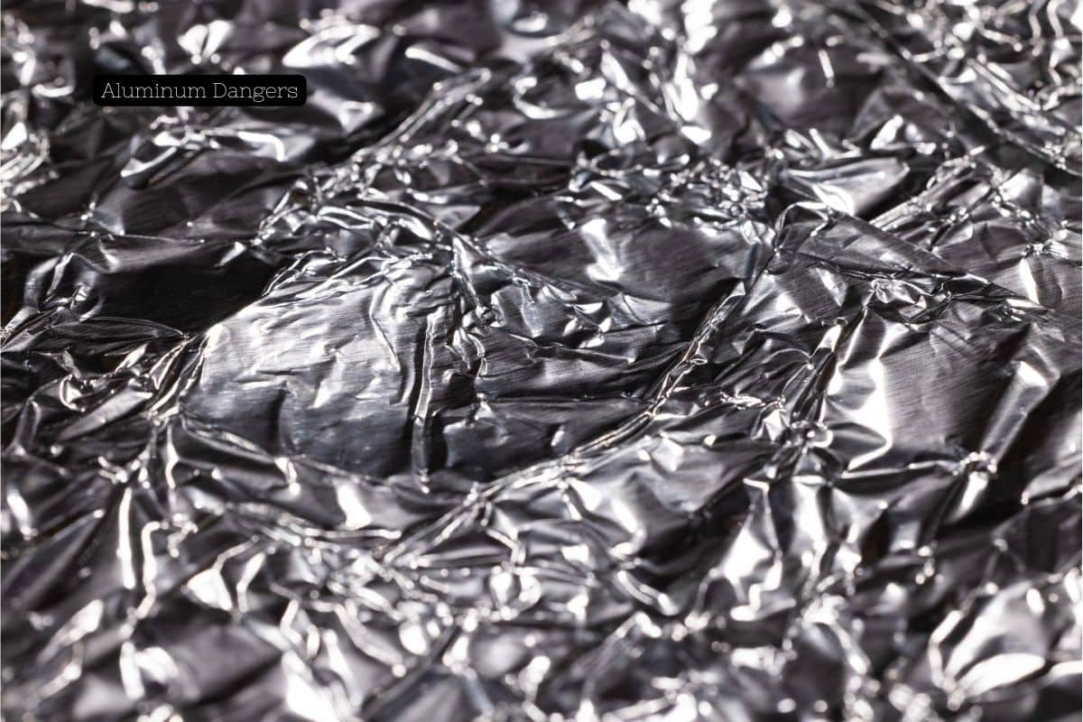 Close-up of crumpled aluminum foil highlighting the text "Aluminum Dangers."