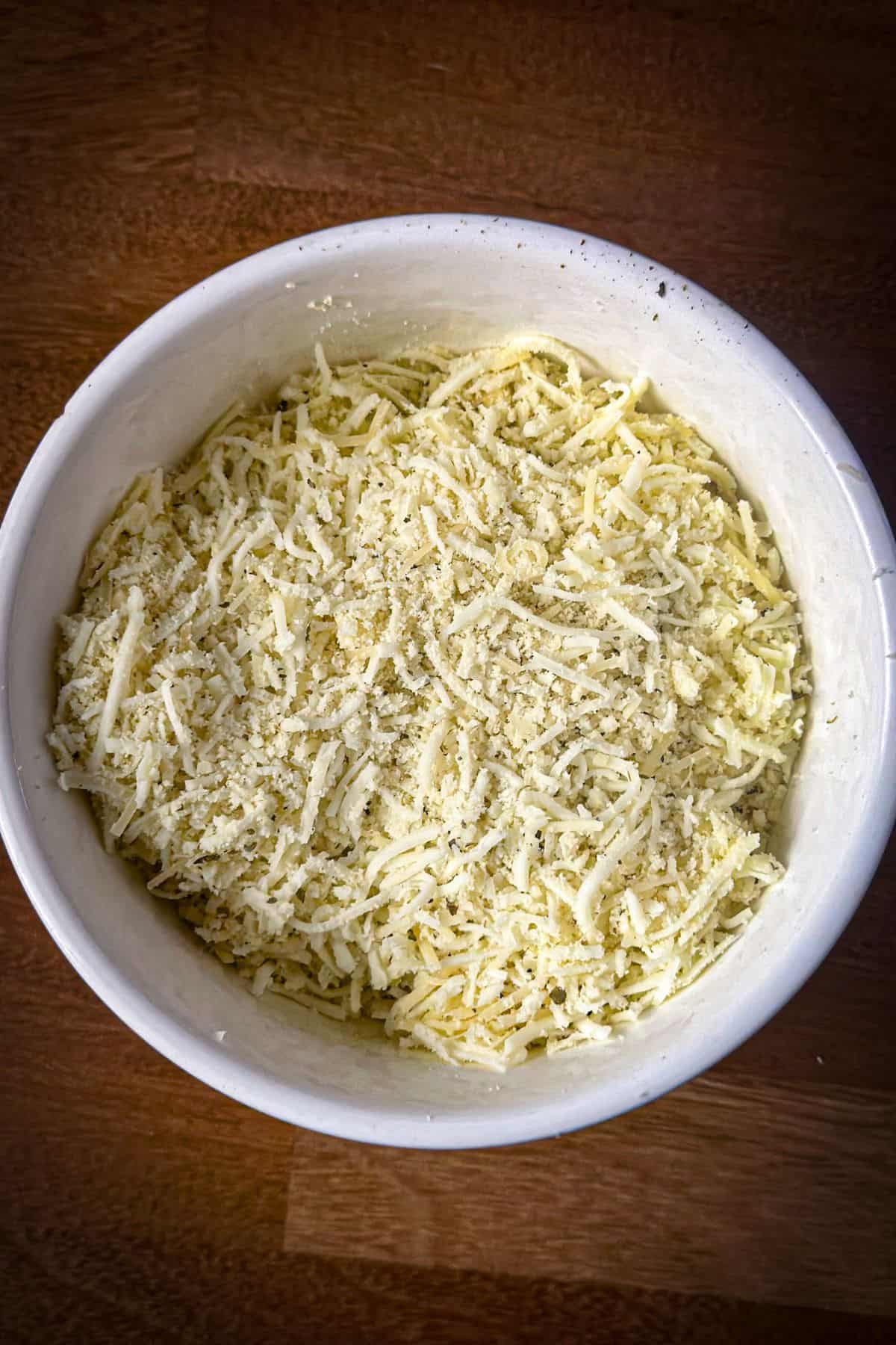 Shredded cheese and seasoning mix in a bowl for the Keto Spinach Artichoke Chicken Casserole topping.