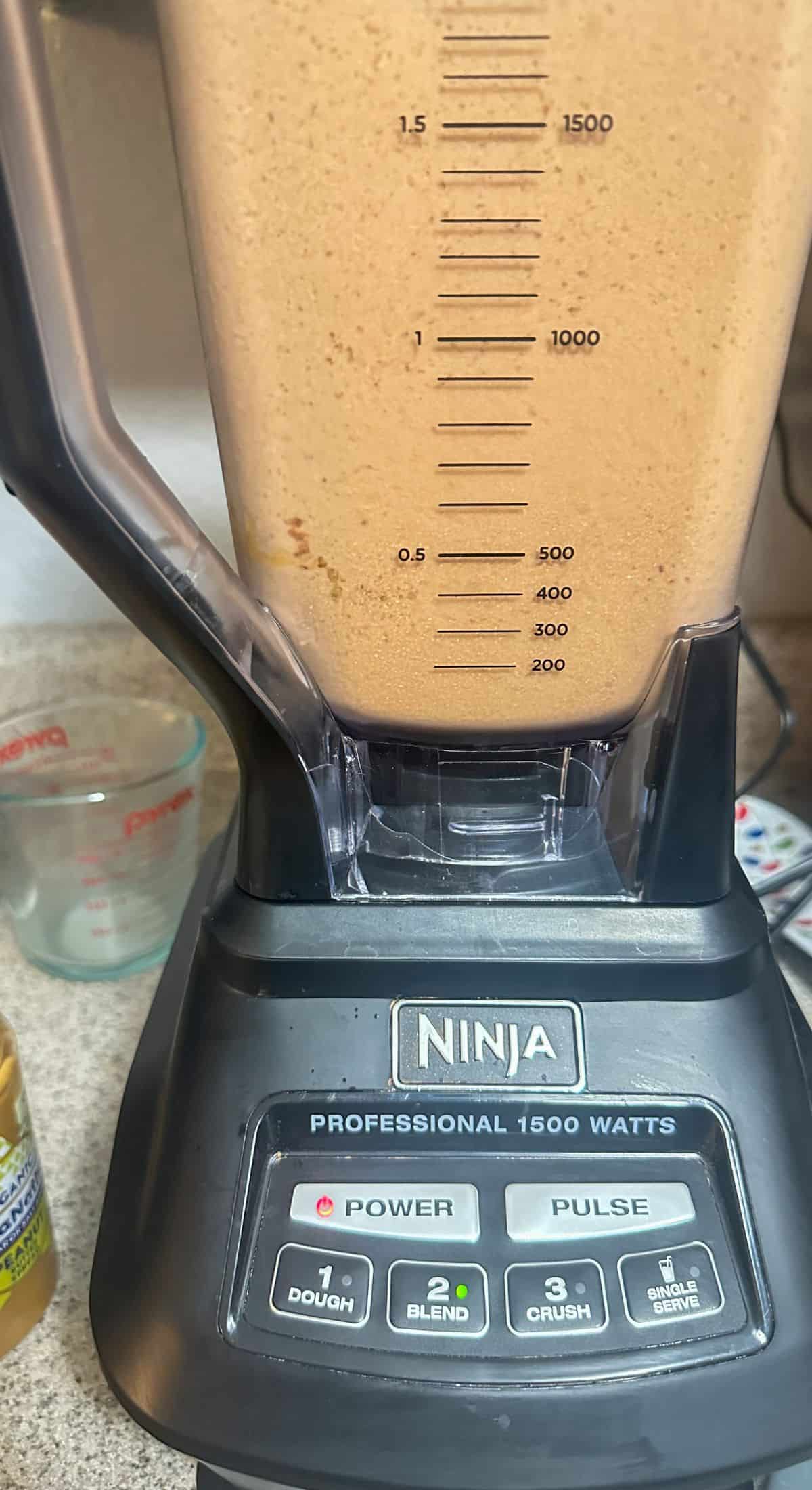 A high-speed Ninja blender filled with a Tropical Smoothie Peanut Butter Cup blend, indicating the smoothie's creamy consistency at the 500 ml mark