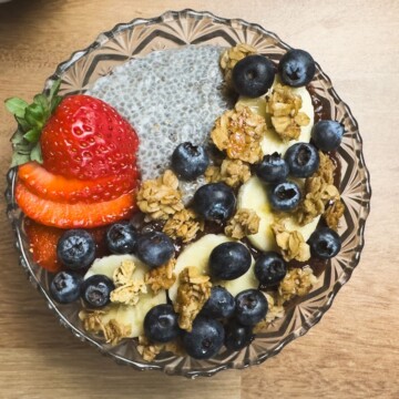 A completed A.M. Superfood Bowl featuring chia seed pudding topped with fresh strawberries, blueberries, banana slices, and granola, ready to be enjoyed