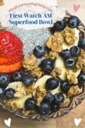 A Pinterest-ready image featuring a 'First Watch AM Superfood Bowl' with glistening chia seeds, golden granola, and ripe strawberries, bananas, and blueberries, all beautifully presented in a glass bowl, with the website 'MindfullyHealthyLiving.com' displayed at the top.