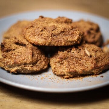 A plate of finished protein snickerdoodle cookies, with a visible coating of cinnamon sugar, presented on a wooden tabletop