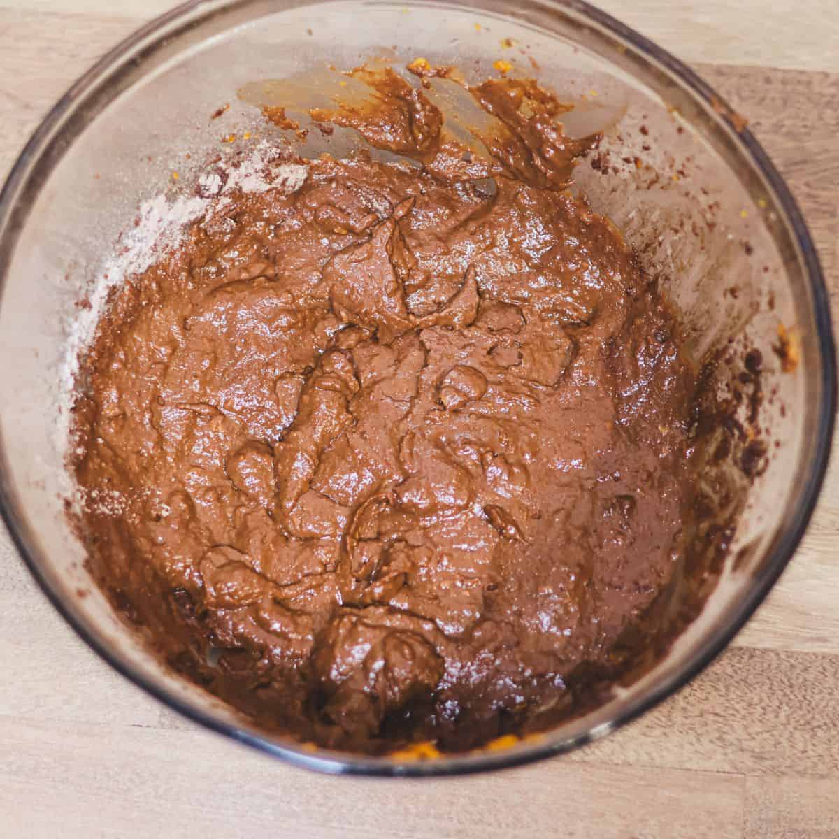 A bowl of mixed brownie batter, rich and chocolatey, ready to be poured into a baking pan.