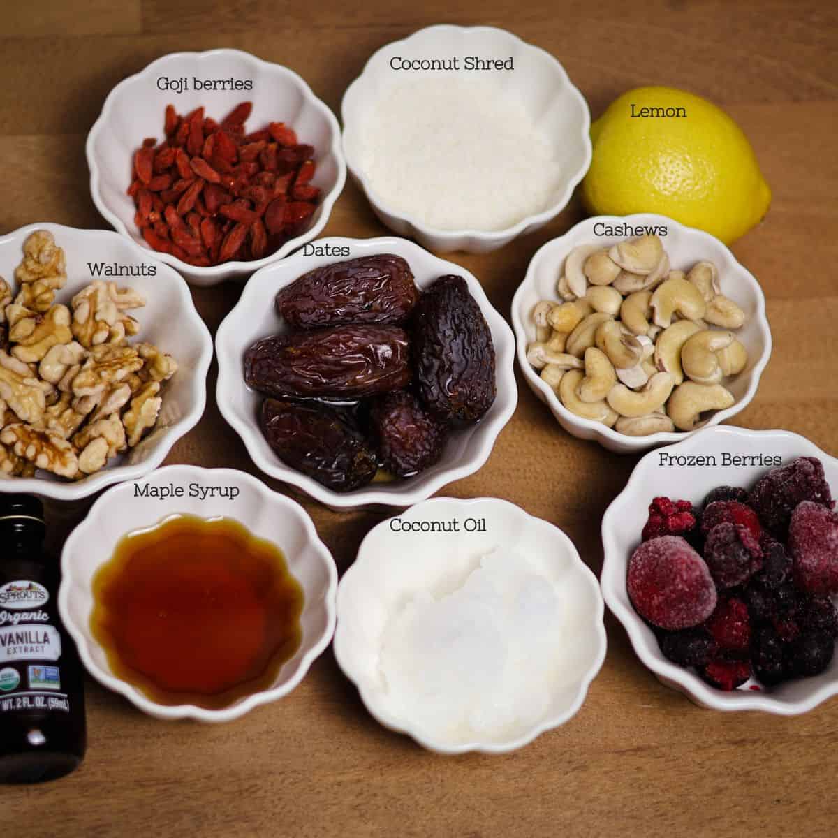Ingredients for no-bake berry cheesecake arranged on a wooden surface, including nuts, berries, and natural sweeteners.