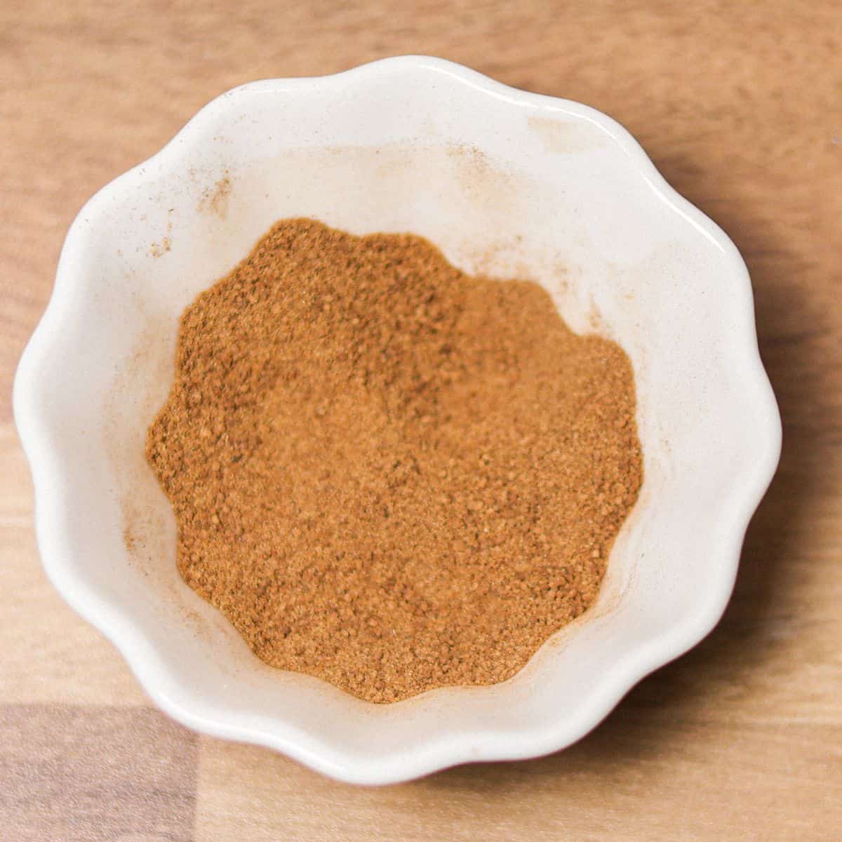 A small white bowl filled with a mix of cinnamon and sugar, ready to be used as topping for snickerdoodle cookies