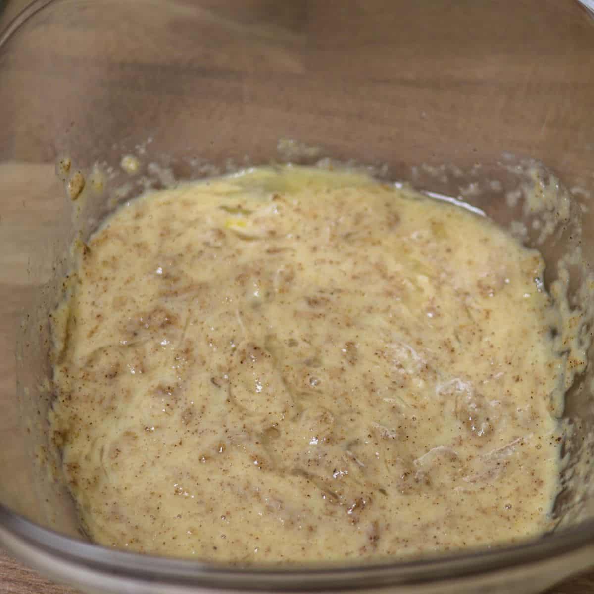 A bowl with wet ingredients for protein snickerdoodle cookies mixed together, forming a creamy, speckled batter.