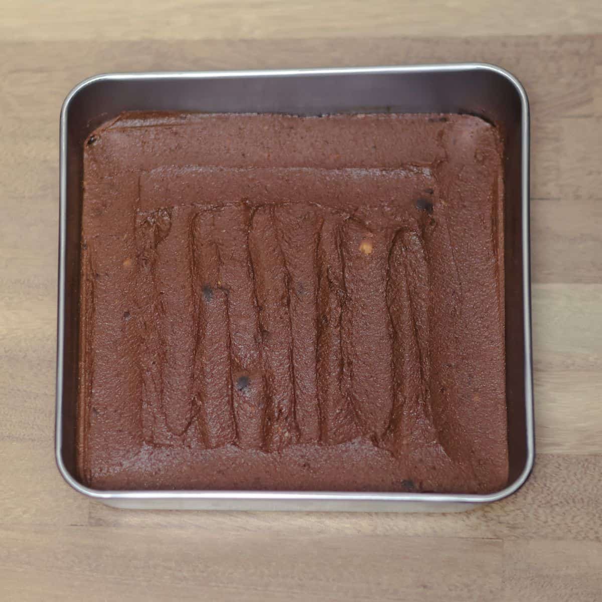 An 8x8 inch baking pan filled with smooth, freshly baked sweet potato protein brownie, showing the even surface of the finished bake.