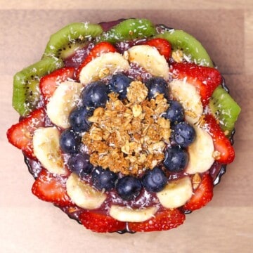 A finished Hawaiian açaí bowl with a colorful arrangement of banana, kiwi, strawberries, and blueberries on top, sprinkled with granola and shredded coconut.