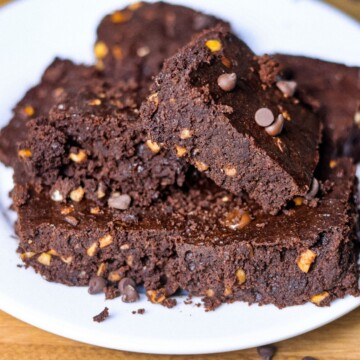 A close-up of a pile of dairy-free gluten-free brownies, showcasing the moist, fudgy texture with nuts and chocolate chips.