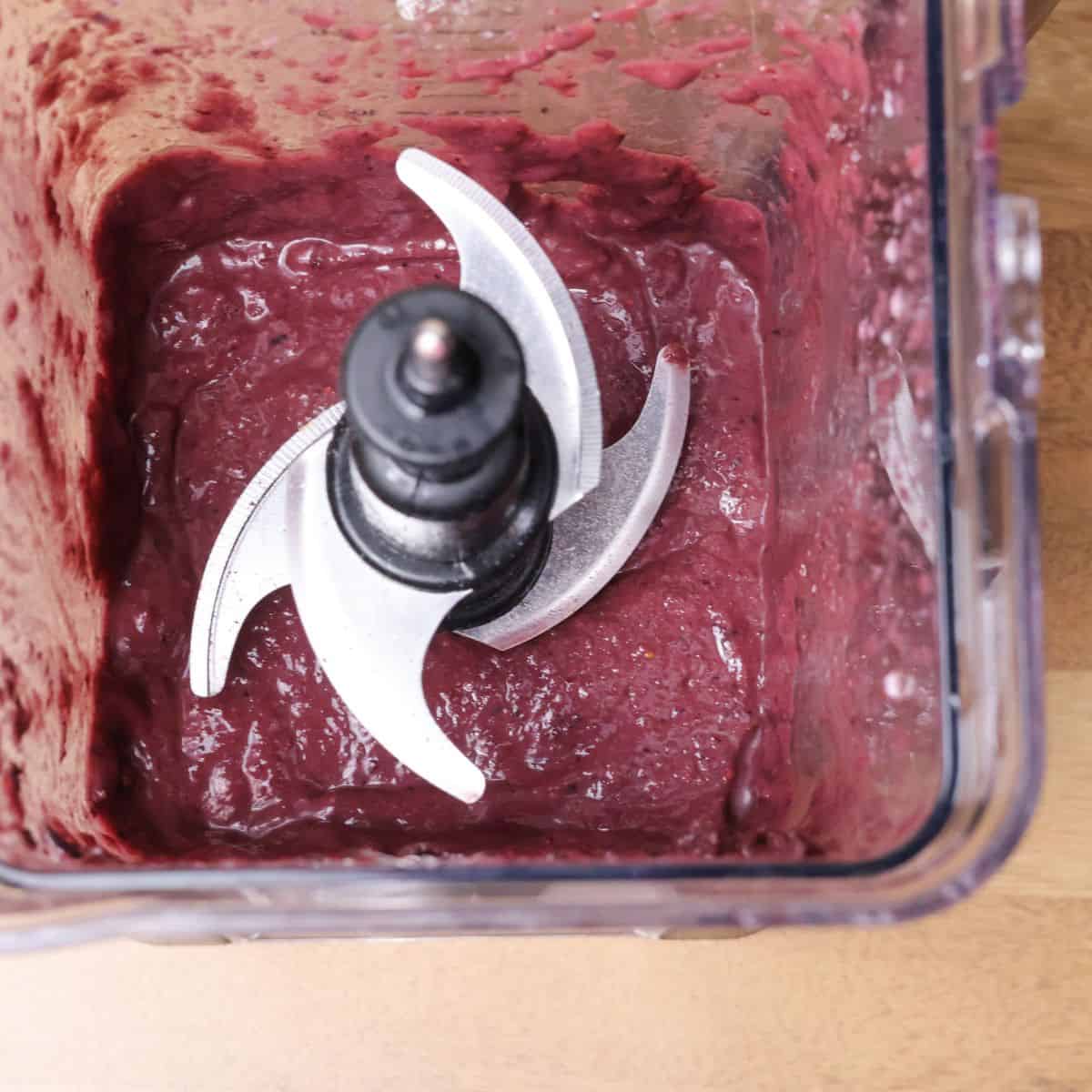 A top view of a blender containing a freshly blended açaí base, showing a smooth, purple mixture.