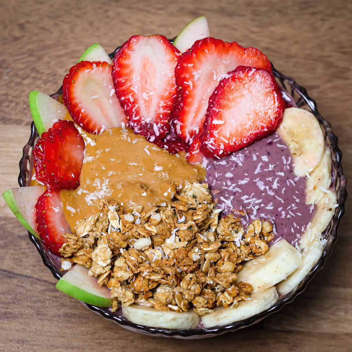 Close-up of the finished acai peanut butter bowl with neat toppings of granola, peanut butter.