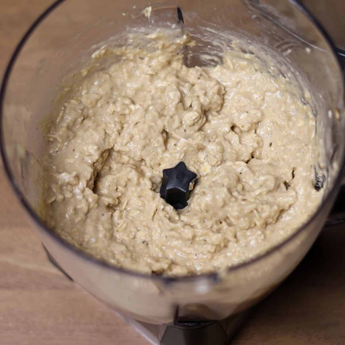Blender filled with the mix of bananas, sprouted oats, and maple syrup blended in a banana bread batter.
