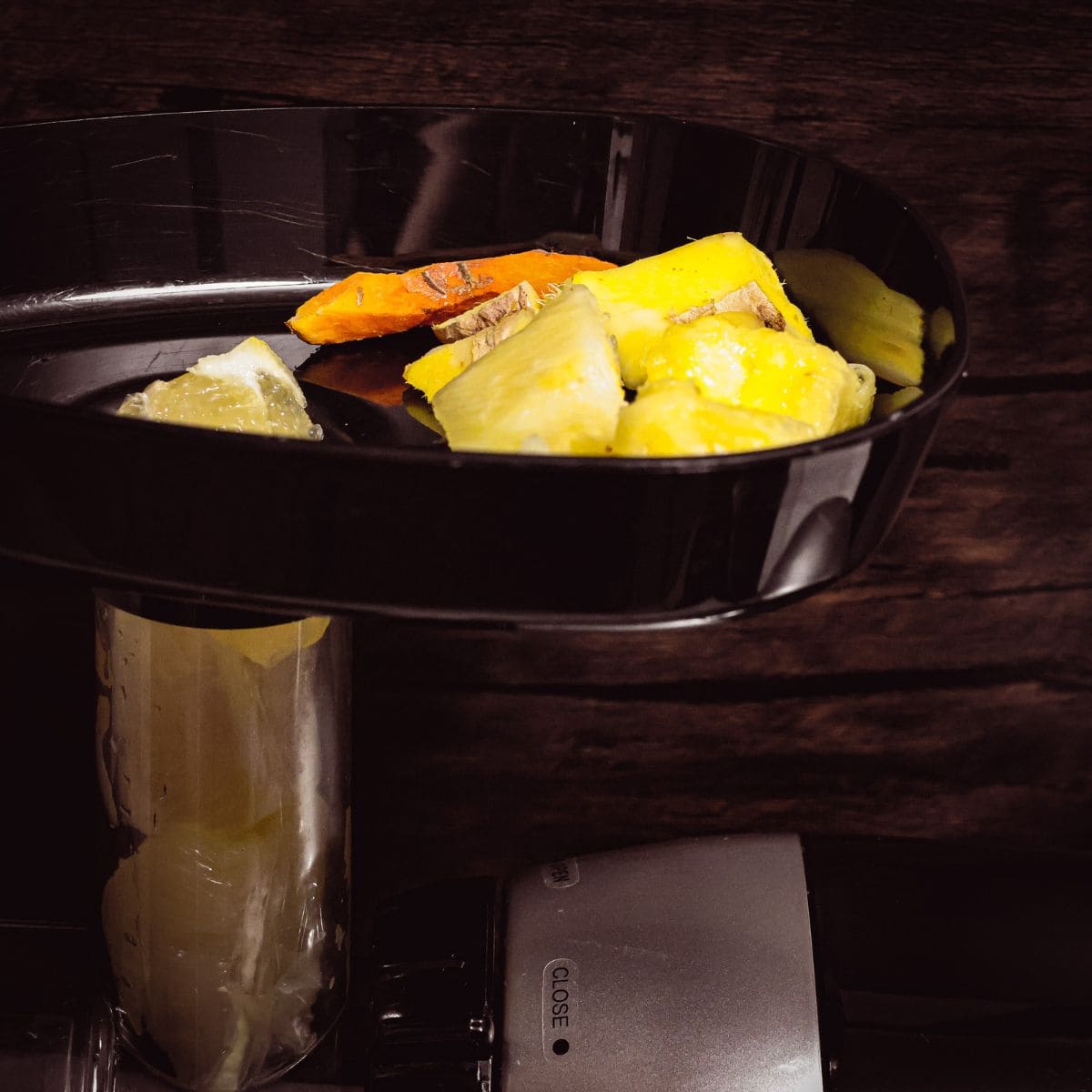Ingredients for an anti-inflammatory juice including ginger, turmeric, and pineapple loaded into the top of a juicer, ready for extraction.