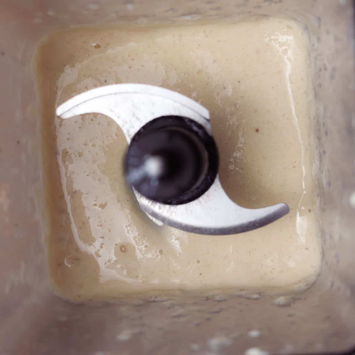 Top view inside a blender showing the initial creamy blend of the Banana Boat Smoothie ingredients.
